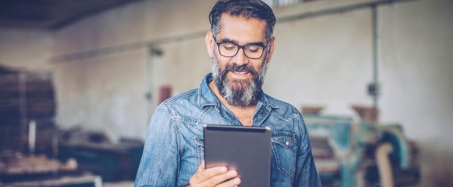 Ein Mann mit Brille hält ein Tablet in der Hand