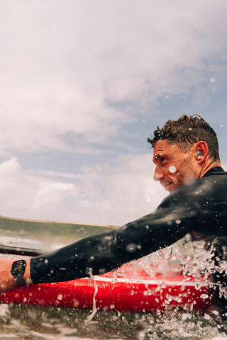 Ein Mann mit einem Paddle Board im Wasser, der eine Apple Watch Series 10 trgt.