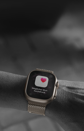 Eine Person trägt die Apple Watch Ultra 3 am Handgelenk, Hinweis zur Gesundheit auf dem Display: Möglicher Bluthochdruck