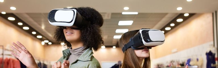 Zwei junge Frauen mit VR-Brillen in einem Bekleidungsgeschäft