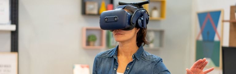 Eine Frau trägt eine VR-Brille und hält einen VR-Controller in der Hand