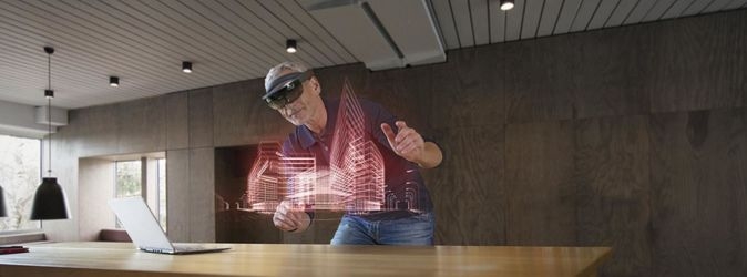 Ein Mann mit AR/VR-Brille arbeitet an dem Gittermodell eines Gebäudes