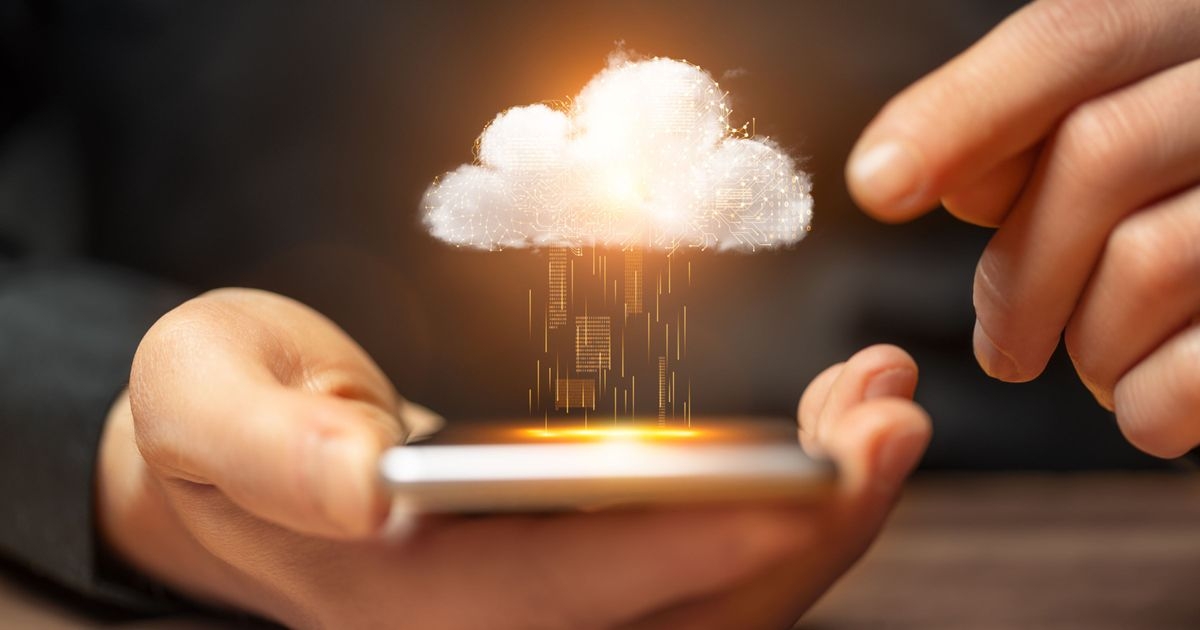 Nahaufnahme eines Smartphones in der Hand. Eine Wolke schwebt über dem Gerät, um das Cloud-Back-up zu symbolisieren.