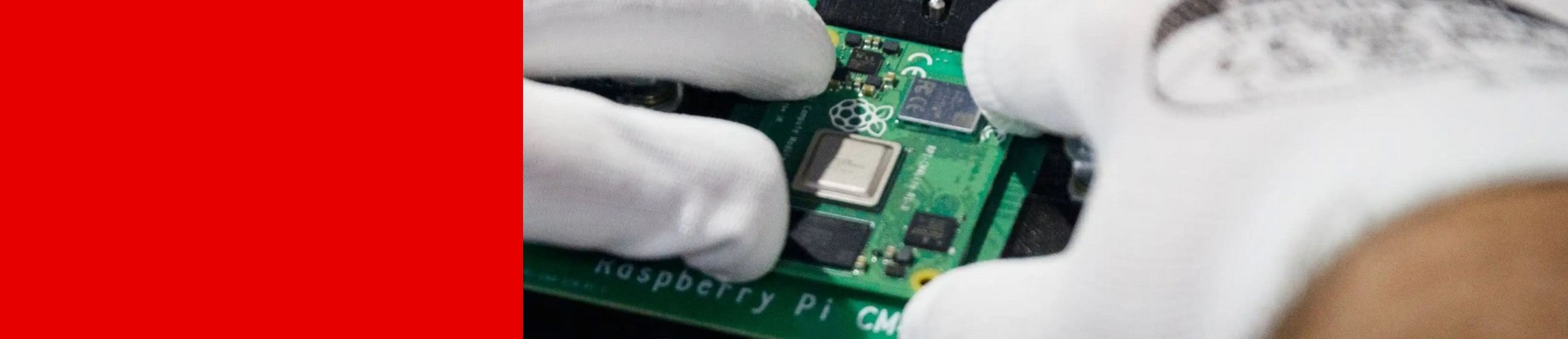 Zwei Hände in antistatischen Handschuhen setzen die Platine eines Raspberry Pi CM in ein anderes Gerät ein.