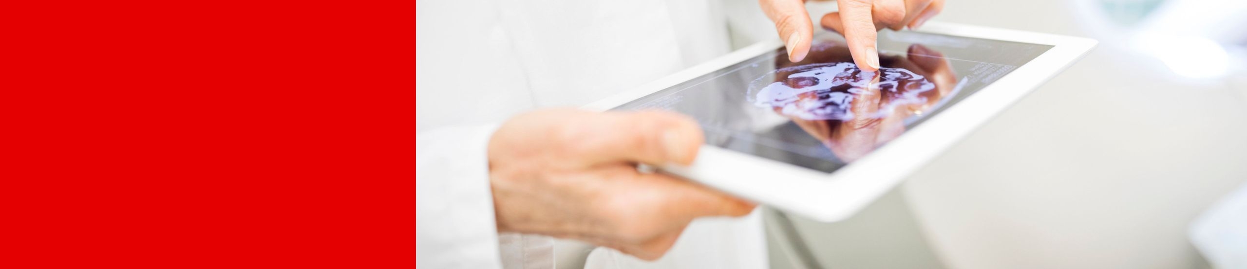 Eine Person in einem weißen Kittel zoomt mit zwei Fingern in eine Abbildung auf einem Tablet.