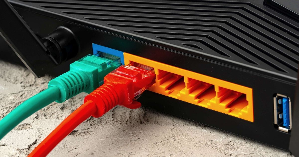 Rückseite eines WLAN-Routers mit WAN- und LAN-Anschlüssen. Ein grünes Ethernet-Kabel steckt im WAN-Anschluss, ein rotes Ethernetkabel steckt in einem LAN-Anschluss.