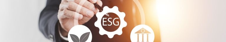 ine Hand zeigt mit einem Kugelschreiber auf ein stilisiertes ESG-Symbol. Um das ESG-Symbol sind weitere Symbole angeordnet. 