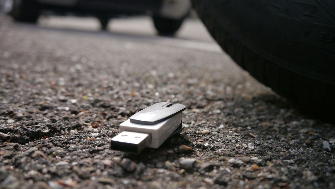  Ein USB-Stick auf einem Parkplatz zwischen Autoreifen