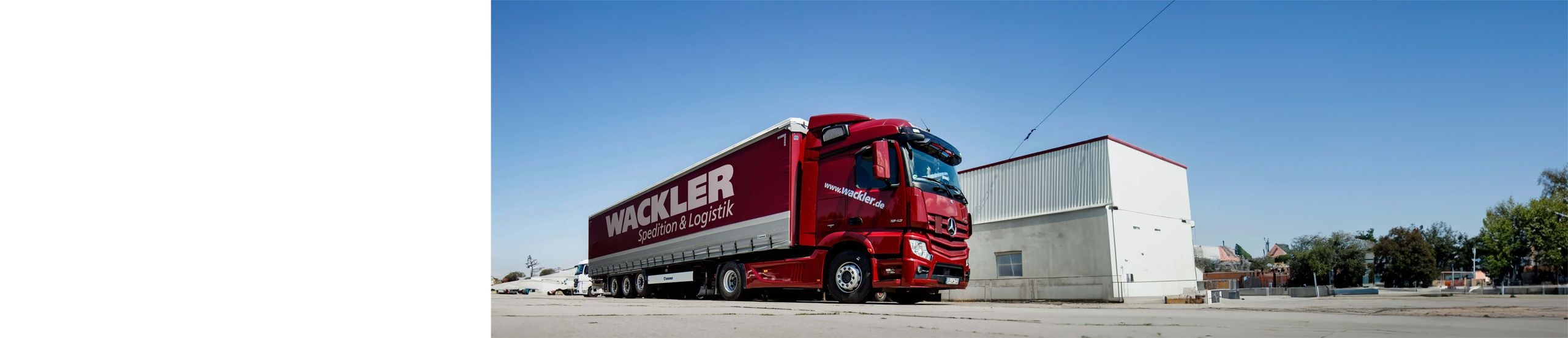 Ein roter LKW der Firma Wackler Spedition & Logistik steht vor einem Gebäude