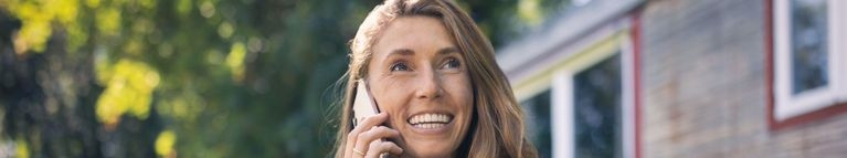 Eine Frau telefoniert mit einem Smartphone und lächelt dabei.