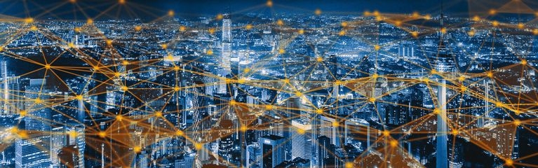 Blick auf eine Stadt bei Nacht, in der alle Geräte symbolisch per IoT-Cloud vernetzt sind