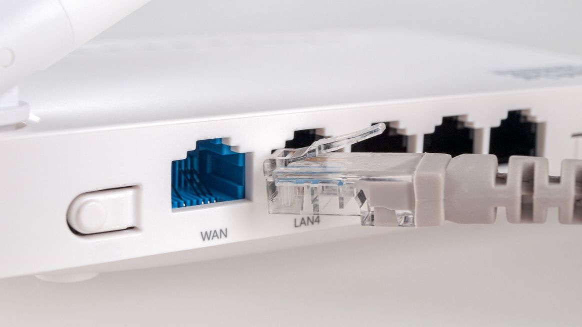 Die Rückseite eines Routers mit den WAN- und LAN-Anschlüssen sowie einem Netzwerkkabel, das man darin einstecken kann