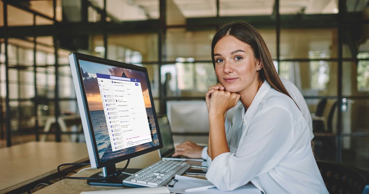 Junge Frau arbeitet an einem Desktop-PC mit Microsoft Teams