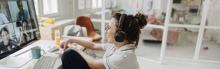 Eine junge Frau sitzt im Homeoffice und nimmt an einer Videokonferenz teil