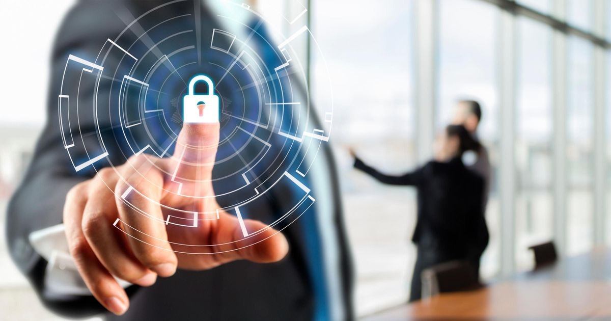 Netzwerksicherheit: Darauf kommt es an Finger zeigt im Vordergrund auf ein virtuelles Schloss-Symbol, im Hintergrund zwei Personen unscharf.