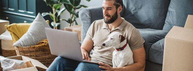 Das Foto zeigt einen Mann und einen Hund, die ein Notebook betrachten