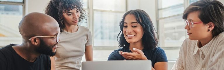 Eine Gruppe von vier Personen diskutiert in einem Büro an einem Laptop