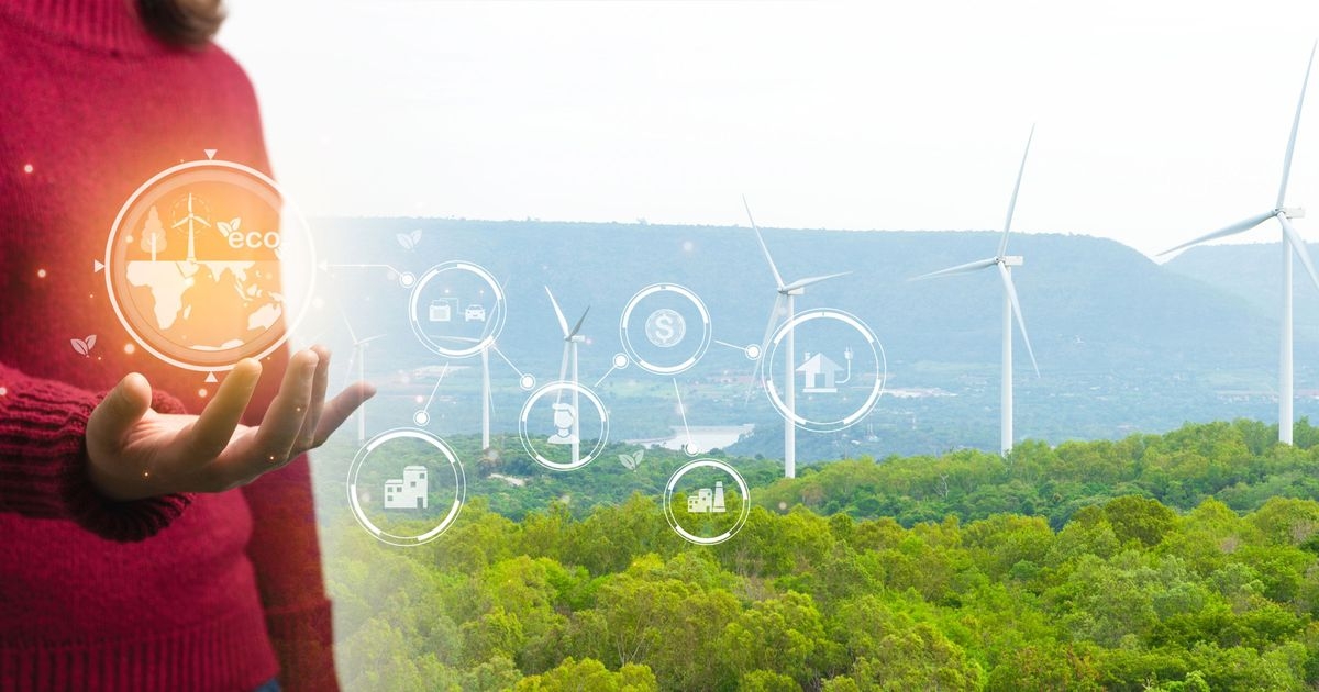 Eine Person in rotem Pullover steht vor einem Windpark. Sie hält die Handfläche nach oben. Im Hintergrund schweben Icons zum Thema Nachhaltigkeit.