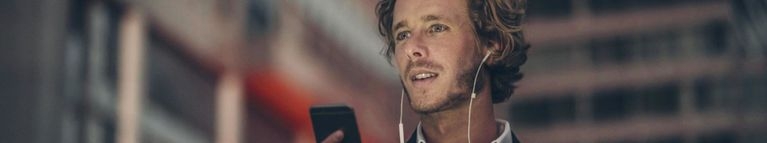 Junger Mann mit Headset am Smartphone