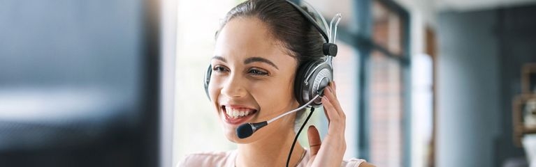 Junge Frau telefoniert mit Headset am Computer