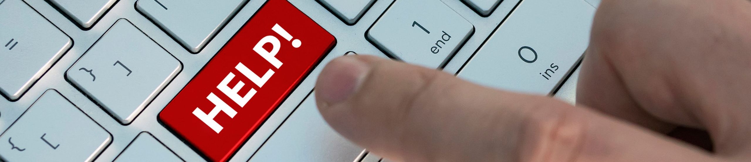 Eine Person drückt einen mit Help beschrifteten Knopf auf einer Tastatur