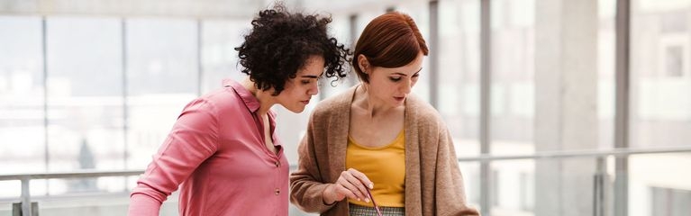 Zwei Frauen stehen an einem Tisch mit dem Modell eines Gebäudes