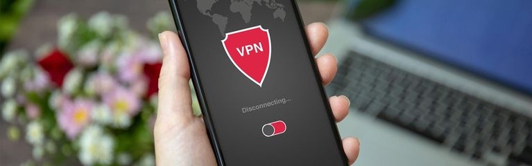 Frauenhände halten ein Smartphone in der Hand. Das Display zeigt ein Schildsymbol mit einem On/Off-Switch für eine VPN-App.