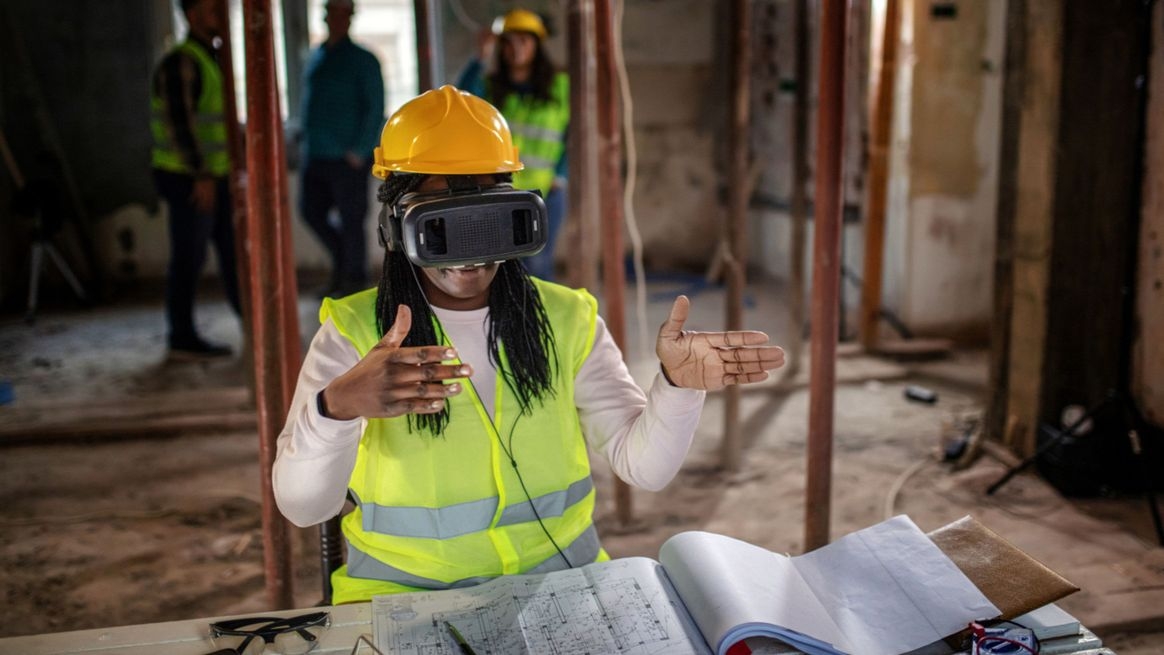 Eine Person mit VR-Headset steht vor einem Bauplan.