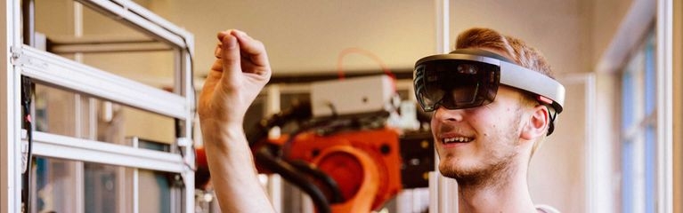 Ein junger Mann trägt eine VR-Brille in einem Raum mit Industriemaschinen