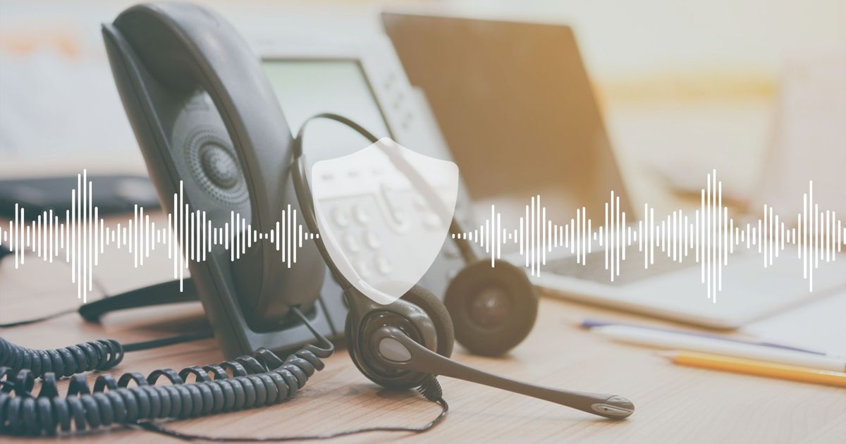 Bürotelefon mit Headset auf einem Schreibtisch. Darüber in weiß Schallwellen von rechts nach links, die von einem Schutzschild unterbrochen werden