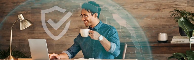 Mann sitzt mit Kaffeetasse in der Hand vor seinem Notebook. Um seinen Arbeitsplatz herum eine Sphäre mit einem Schutzschild-Symbol