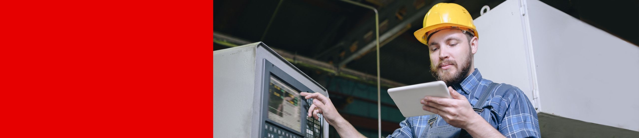 Ein Mann mit gelbem Schutzhelm bedient mit einer Hand eine Fabrikmaschine und hält in der anderen Hand ein Tablet.