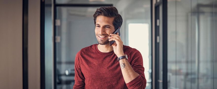 Mann im roten Pullover, der im Büro telefoniert