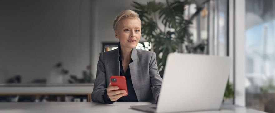 Frau am Laptop mit Handy