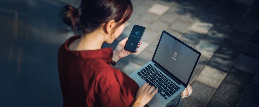 Frau am Laptop mit Handy