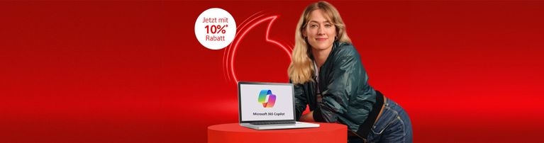 Auf dem Bild ist eine lächelnde Frau zu sehen, die sich auf einen runden, roten Tisch lehnt. Auf dem Tisch steht ein Laptop, auf dessen Bildschirm das Logo von Microsoft 365 Copilot zu sehen ist.