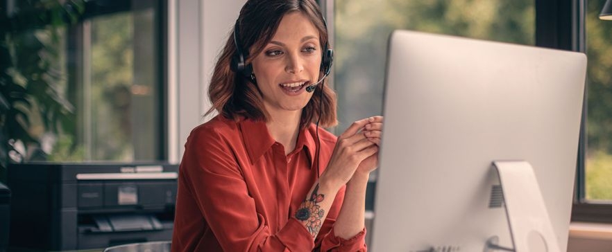 Frau in roter Bluse mit Headset macht einen Videocall