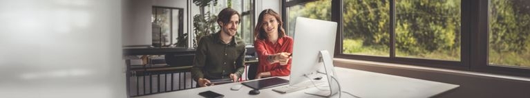 Zwei junge Menschen sitzen vor einem Computer 