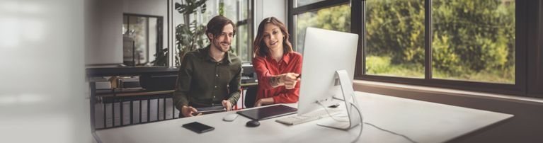 Herr und Dame sitzen arbeitend an einem PC