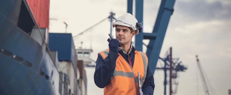 Ein Bauingenieur steht mit Walkie Talkie im Hafen