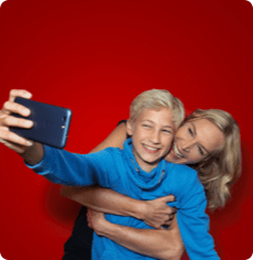 Ein Junge mit einem Smartphone, der ein Selfie von sich und seiner Mutter macht